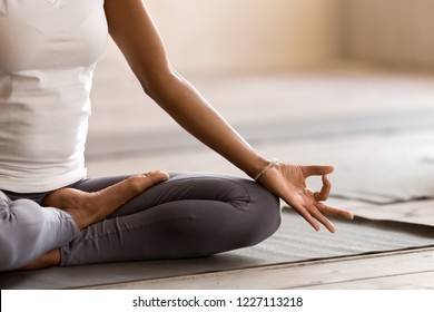 Yogi schwarze Frau, die Yogastunde praktiziert, atmet, meditiert, Ardha Padmasana-Übung macht, halbe Lotus-Pose mit Mudra-Geste, trainiert, Indoor-Nahaufnahme. Wohlbefinden, Wellnesskonzept