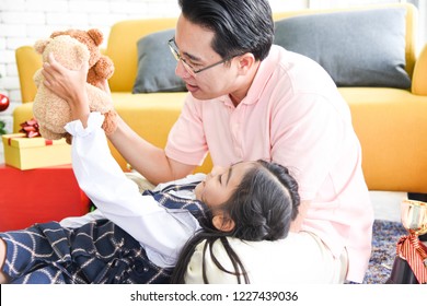 The daughter lies on her father's lap. Dad and daughter are playing teddy bear together very fun and happy on Christmas day.Concept Christmas Day, Family Day, Christmas Eve , Happy New Year