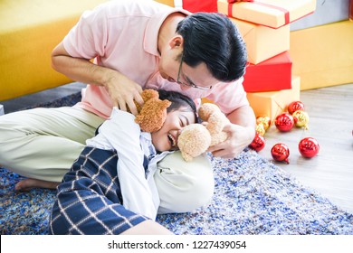The daughter lies on her father's lap. Dad and daughter are playing teddy bear together very fun and happy on Christmas day.Concept Christmas Day, Family Day, Christmas Eve , Happy New Year