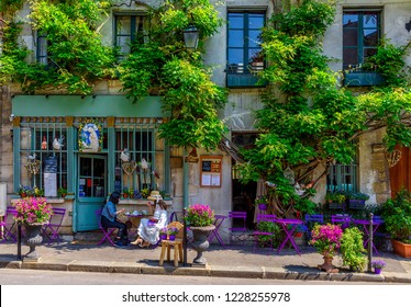 Cozy street with flowers and tables of cafe  in Paris, France