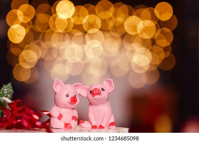 zwei rosa Schweinefiguren an den Hintergrundlampengirlanden. das Symbol des neuen Jahres, das Jahr des Schweins