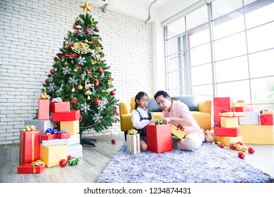 Dad and daughter opening a gift box on Christmas Day. Daughter is excited, the gift is in the box very much. She is happy to receive gifts from her father. Concept Christmas Day, Family Day