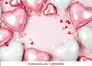 Air Balloons of heart shaped foil on pastel pink background. Love concept. Holiday celebration. Valentine's Day or wedding/bachelorette party decoration. Metallic balloon