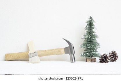 メリー クリスマスと新年あけましておめでとうございます便利なツールの背景概念、ハンマーとペイント ブラシ クリスマス ツリーと松ぼっくりの装飾が施された木材にコピー スペース。