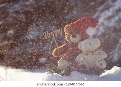 Teddybär mit einer Freundin, die in einem winterlichen Nadelwald sitzt und ein Schild "Happy" hält, feiert Weihnachten und das neue Jahr. Schneesturm im Wald.