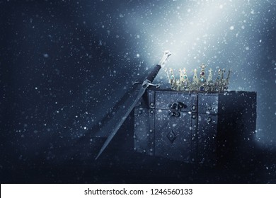 mysterieus en magisch beeld van oude kroon, houten kist en zwaard over gotische zwarte achtergrond. Middeleeuwse periode concept