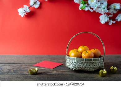 Các phụ kiện trên nền khái niệm kỳ nghỉ Tết Nguyên đán và Tết Nguyên đán. Màu cam trong giỏ gỗ với tiền bỏ túi màu đỏ và hoa trên phông nền màu nâu và đỏ mộc mạc hiện đại tại studio bàn làm việc tại nhà.
