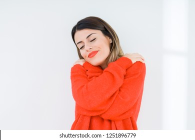 Young woman wearing casual red sweater over isolated background Hugging oneself happy and positive, smiling confident. Self love and self care