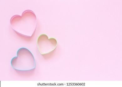 パステル ピンクの背景にハート型の 3 色のカッター クッキー。コンセプト バレンタイン カード。トップ ビュー テキスト用のスペースをコピーします。