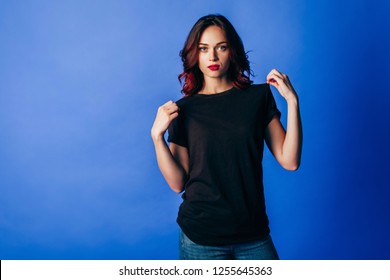 青の背景にスタジオで黒の t シャツでポーズをとる美しい少女。ロゴの場所