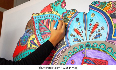 naby, 'n hand van 'n donkerkop vrou, gekleurde deel van 'n Afrika-vormige mandala, met gekleurde merkers