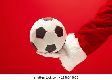 Santa Claus sosteniendo una pelota de fútbol aislado sobre fondo rojo studio