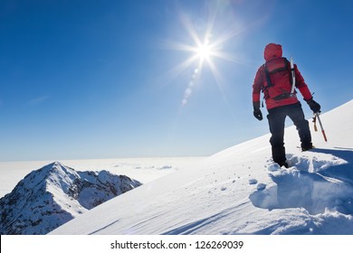 登山家は、晴れた冬の日に雪山の頂上に到達します。西アルプス、ビエッラ、イタリア。