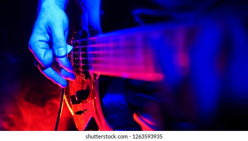 ロックコンサート。ギタリストは、ギターを弾きます。鮮やかなネオンに照らされたギター。手に焦点を当てる