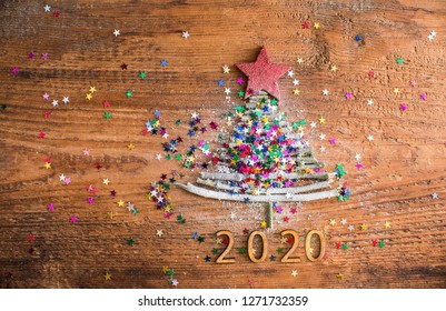 Zeichensymbol von vielen trockenen Stockweihnachtsgrün-Baum viele bunte Sternspielzeuge auf altem Retro-Weinlesehilfholzhintergrund. Leerer Kopierplatz für die Beschriftung. Idee für ein frohes neues Jahr 2020 Urlaub.