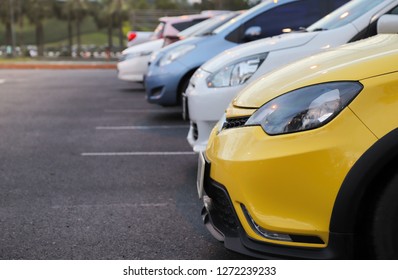 Close-up van de voorkant van de gele auto en andere auto's die parkeren op de parkeerplaats met natuurlijke achtergrond na regen in de avond van een zonnige dag.