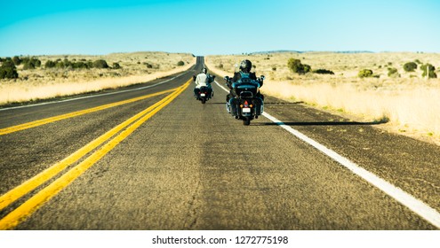 Berømt amerikansk historisk vej mod vest - Route 66 med to silhuetter af motorcyklister, der kører deres motorcykler (på vej mod nordøst) Sydcaliforniens ørkenlandskabsbaggrund, USA