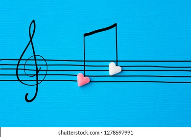 創造的なバレンタインのグリーティング カード。シュガー ハート形キャンディー手描き落書きスケッチ リネン テクスチャ青い紙の背景にスタッフ ト音記号の音符。ラブソングのロマンチックなコンセプト
