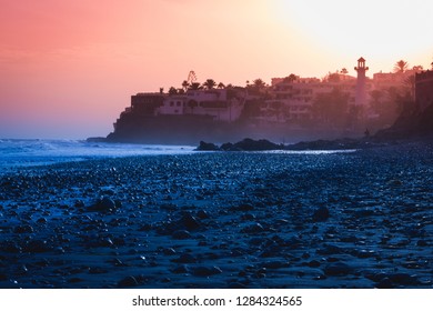 グラン カナリア島のプラヤ デル アギラの小石の多い海岸に幻想的な夕日。カナリア諸島、スペインの空のビーチでカラフルな夕暮れ