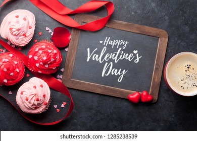 Tarjeta de felicitación del día de San Valentín con deliciosos cupcakes dulces y taza de café sobre fondo de piedra. Vista superior