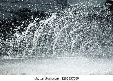 Xe chuyển động qua vũng nước lớn bắn ra từ bánh xe trên đường phố. kết cấu mưa nước
