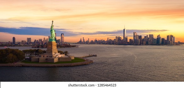 Patung Liberty di kota New York dengan latar belakang manhatttan dan matahari terbenam, New York, AS