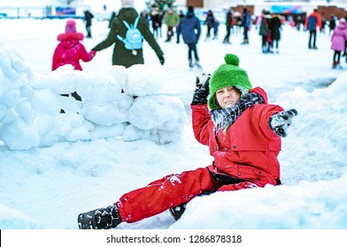 An angry funny boy throws snowballs and builds a snow fort near the city skating rink. Winter activities