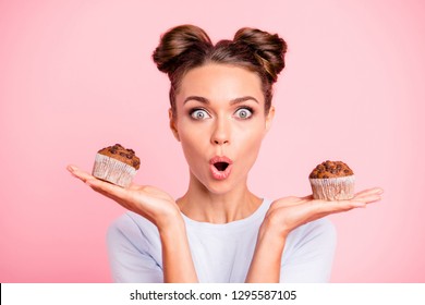 Close-up portret van mooie mooie schattige aantrekkelijke verbaasd bang bang meisje in handen twee taarten te kiezen beslissend dilemma geopende mond geïsoleerd over roze pastel achtergrond