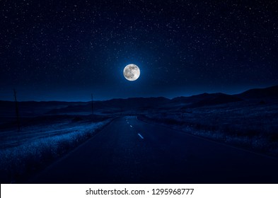 Mountain Road durch den Wald in einer Vollmondnacht. Szenische Nachtlandschaft der Landstraße nachts mit großem Mond