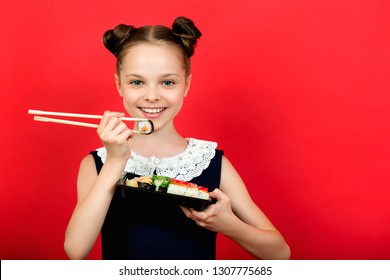 Cute smiling little girl with with sushi on  red background.  Student child girl eating sushi and rolls - commercial concept.