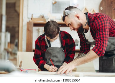勤勉な少年は、他の楽器と一緒に木の工房に座って大工として働いている父親と一緒に、鉛筆で木の板の測定とマーキングに忙しい.