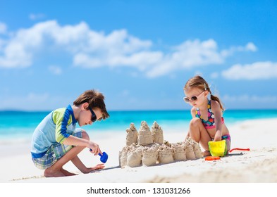 熱帯のビーチで砂の城を作る兄と妹