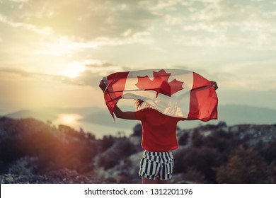 日没で走りながらカナダの旗を振って幸せな子供の 10 代の少女