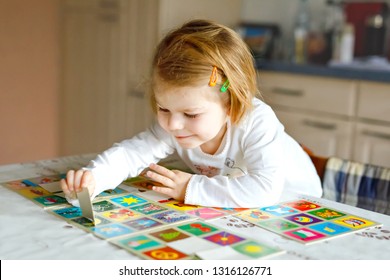 เด็กหญิงวัยเตาะแตะน่ารักน่าชังกำลังเล่นเกมไพ่ภาพที่บ้านหรือที่ห้องเด็ก เด็กๆ มีสุขภาพดี ฝึกความจำ ความคิด ขั้นตอนการพัฒนาและการศึกษาของเด็ก