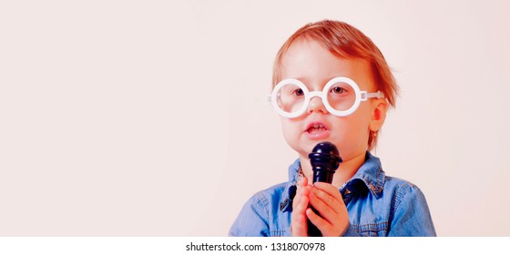 The famous actress. Humorous photo of little cute child girl singing with a microphone. Happy childhood, music, child development concept. Free space for text.