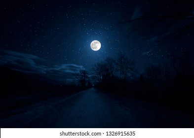 Mountain Road durch den Wald in einer Vollmondnacht. Szenische Nachtlandschaft der Landstraße nachts mit großem Mond