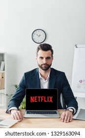 красив съветник в костюм, показващ лаптоп с уебсайта на Netflix на екрана