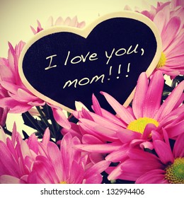 Satz Ich liebe dich, Mama, geschrieben mit Kreide auf einer herzförmigen Tafel auf einem Strauß rosa Chrysanthemen, mit Retro-Effekt
