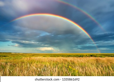 嵐の空にかかる虹。夏の日の田舎の暗い嵐の空に虹がかかる田園風景。