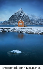 A classic and beautiful landscape of the Lofoten Islands in Sakrisøy, with a yellow house in front of the sea and high mountains in the background, Northern Europe, Norway 
Traditional rorbu house