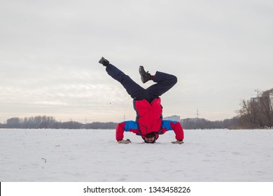 Un hombre de mediana edad practica yoga en un río helado. Shirshasana (parada de cabeza). Ulyanovsk, Rusia.