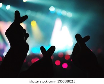 K-Pop müzik teması veya Canlı konser arka planı, sanatçının desteklediği izleyicilerin Kore tarzı mini kalp şeklinde el hareketi yaptığı bulanık izleyici ve sahne üzerinde ışık efektleriyle.