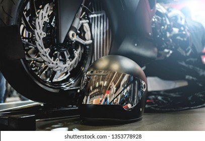 黒いオートバイのヘルメットが床に立ち、オートバイが背景にある.