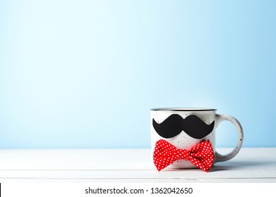 Taza de café con bigote y pajarita roja sobre fondo azul, concepto del día del padre feliz