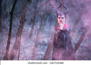 煙のような背景を持つ春の空の森でポーズをとる角を持つ魔法の凶悪な女性。横長の画像合成
