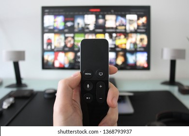 Tangan memegang remote TV sambil menonton acara di layanan streaming di Televisi.
