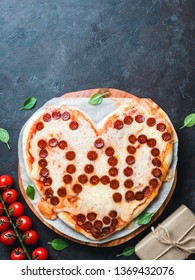 Father's day background with pizza in heart shape and dad word. Pepperoni pizza in heart-shape with dad lettering and gift box on dark background.Copy space.Father day concept,recipe and idea.Vertical