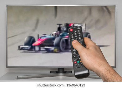 Gara në Formula 1 në TV dhe dora e njeriut me telekomandë TV