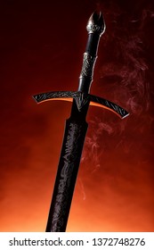 Espada de ferro antiga fotografada em close-up sobre um fundo escuro.