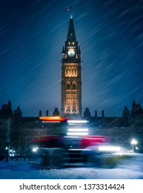 OTTAWA, CANADA - Canadian Parliament Hill Government building in winter snow storm. Cold, frozen scene with plow transport driving past Peace Tower, Houses, senator buildings. Ottawa, Ontario, Canada